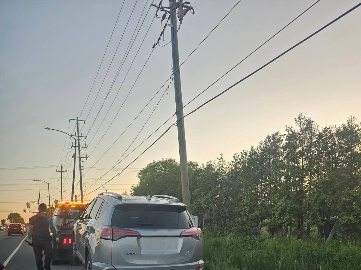 Most Valuable Towing truck with warning lights towing a silver SUV on a tree-lined road at dusk